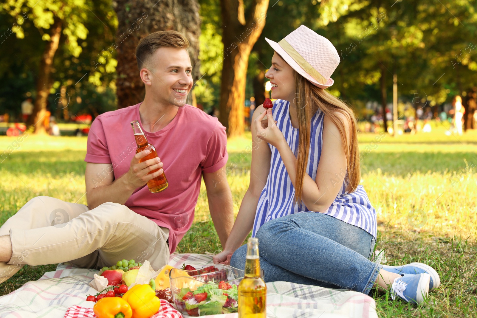 Photo of Young couple enjoying picnic in park on summer day