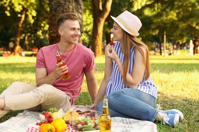 Young couple enjoying picnic in park on summer day