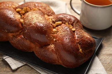 Photo of Delicious yeast dough cake and cup of tea on wooden table, closeup