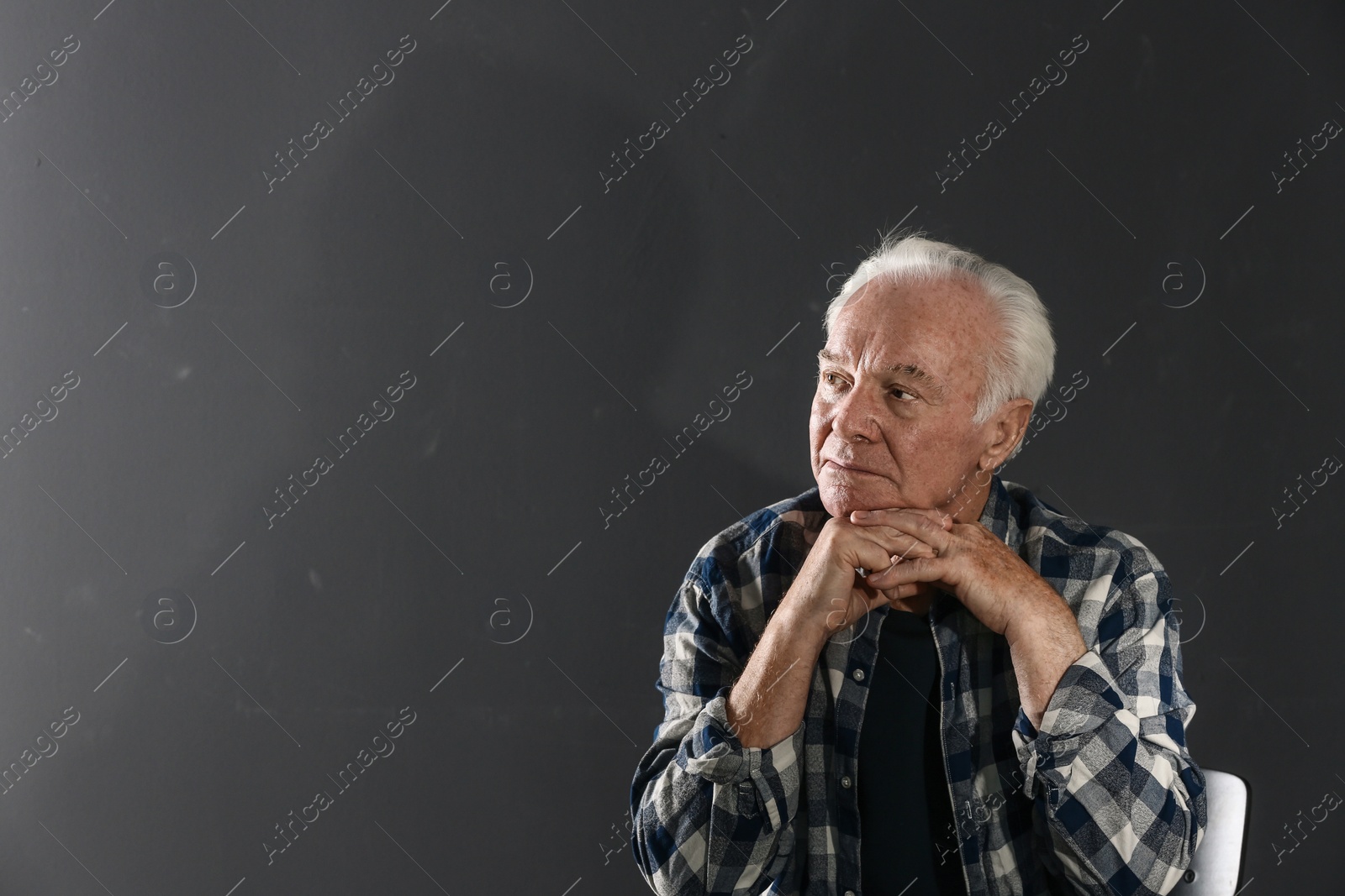Photo of Portrait of poor elderly man on dark background. Space for text
