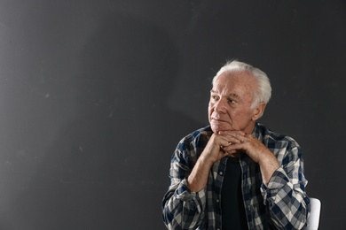 Portrait of poor elderly man on dark background. Space for text