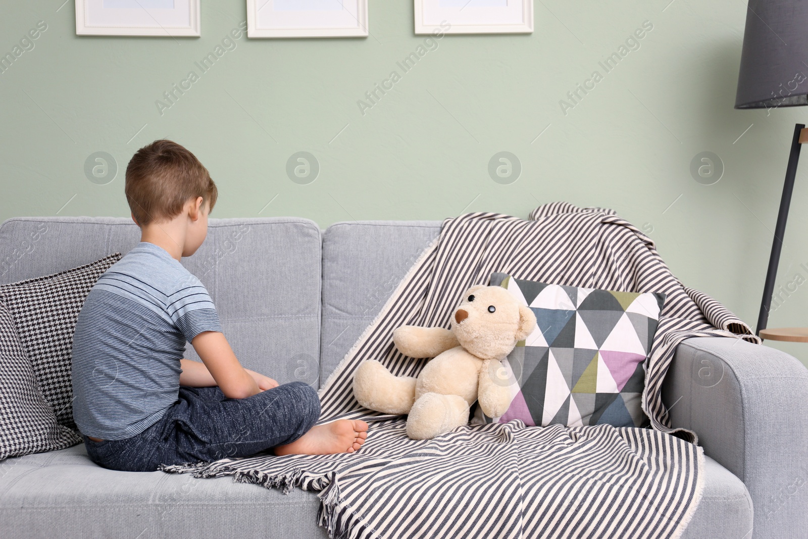 Photo of Lonely little boy sitting on sofa at home. Autism concept
