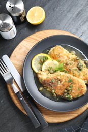 Photo of Delicious chicken piccata served on black table, flat lay