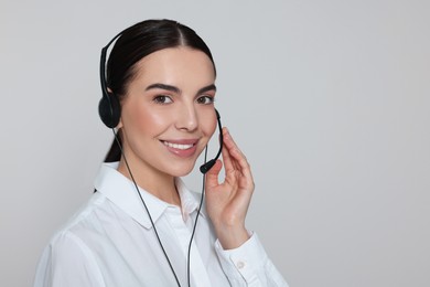 Photo of Hotline operator with modern headset on light grey background, space for text. Customer support