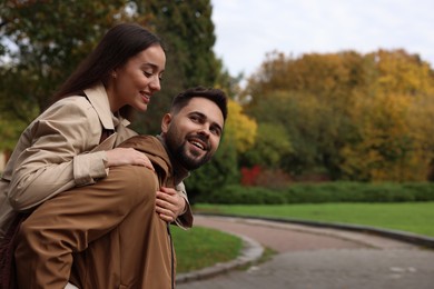 Romantic young couple spending time together in autumn park, space for text