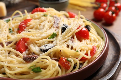 Photo of Delicious pasta with anchovies, tomatoes and parmesan cheese on table, closeup