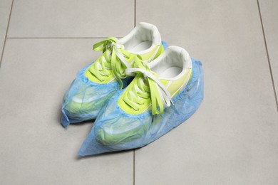 Photo of Sneakers in blue shoe covers on light floor