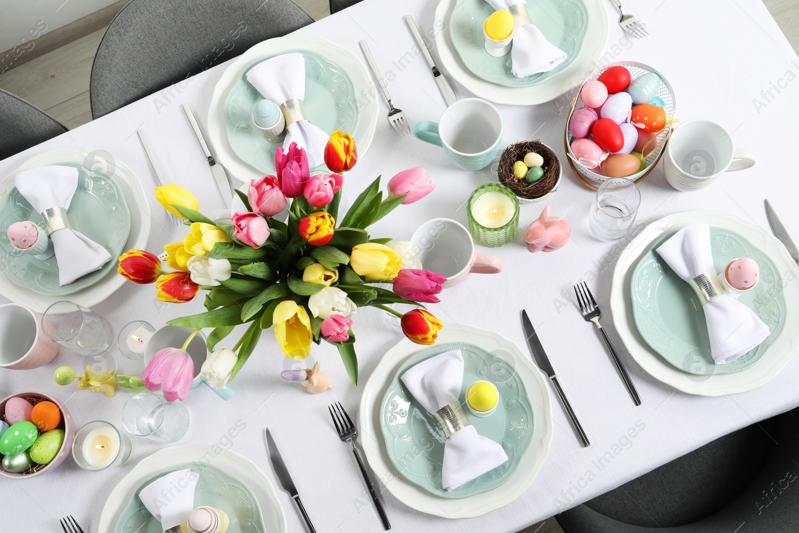 Photo of Festive Easter table setting with beautiful flowers and painted eggs, top view