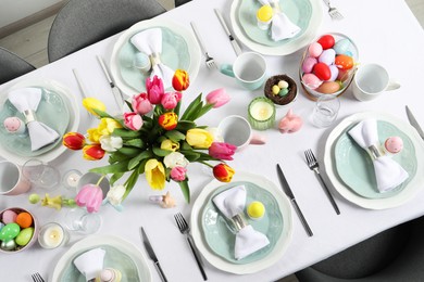 Festive Easter table setting with beautiful flowers and painted eggs, top view