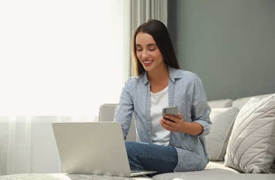 Photo of Woman with modern smartphone and laptop at home. Searching information
