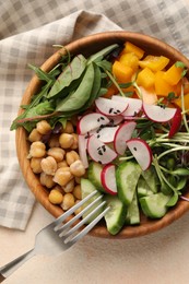 Delicious vegan bowl with cucumbers, chickpeas and radish on beige table, top view
