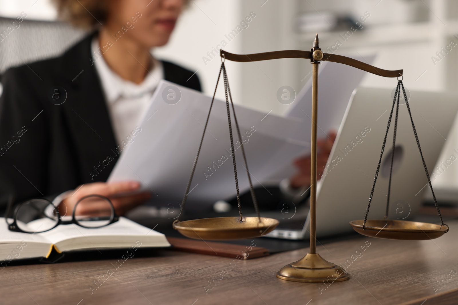 Photo of Notary working with documents at workplace in office, focus on scales of justice