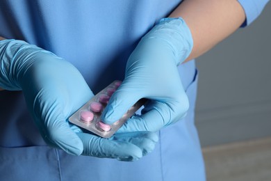 Doctor taking pill out from blister pack on grey background, closeup