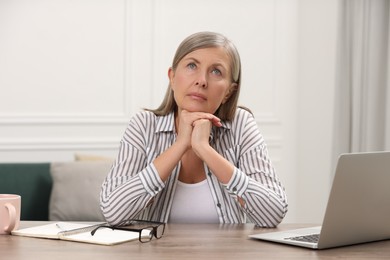 Photo of Menopause, mood changes. Sad woman at wooden table indoors