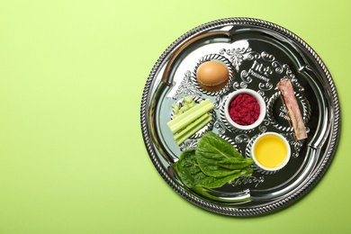 Passover Seder plate (keara) with symbolic meal on green background, top view. Pesah celebration