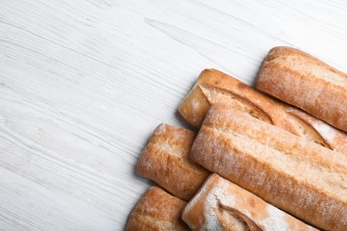 Photo of Tasty baguettes on white wooden table, flat lay. Space for text