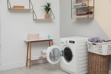 Modern washing machine in laundry room interior