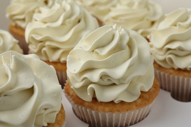 Photo of Tasty cupcakes with vanilla cream in box, closeup