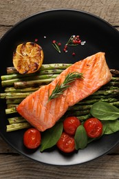 Photo of Tasty grilled salmon with tomatoes, asparagus and spices on table, top view