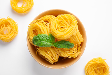 Photo of Angel hair pasta and basil leaves on white background, top view