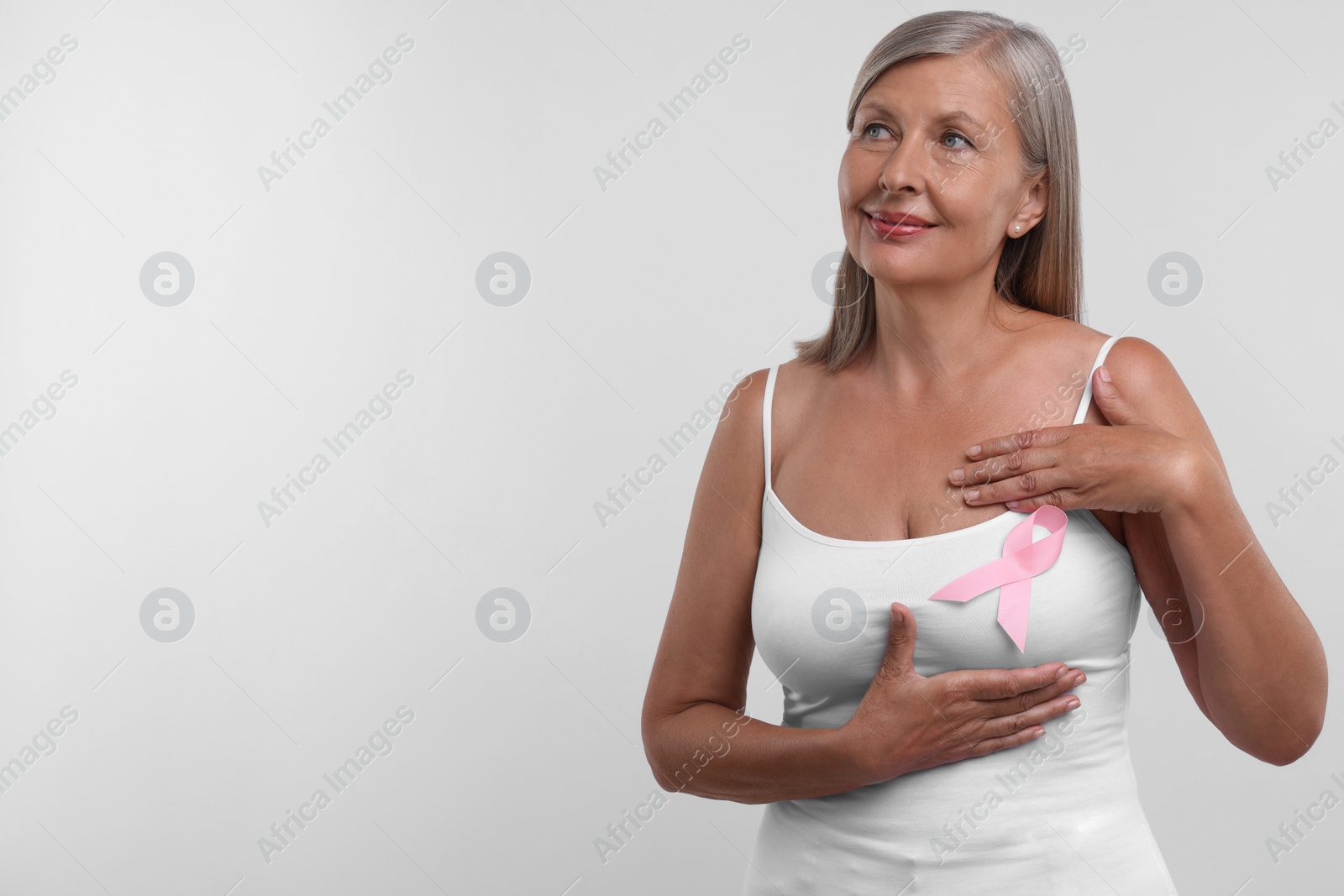 Photo of Beautiful senior woman with pink ribbon on white background, space for text. Breast cancer awareness