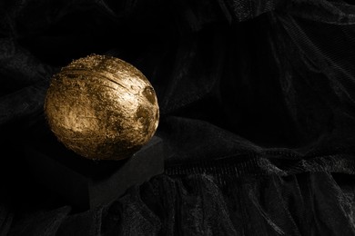 Photo of Golden coconut on black fabric. Space for text