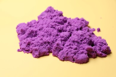 Photo of Violet kinetic sand on beige background, closeup