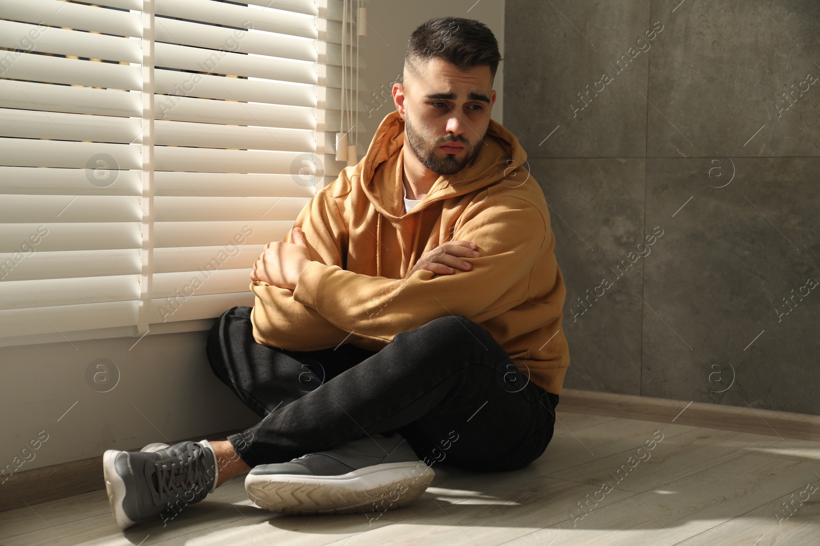 Photo of Sad man sitting on floor near window