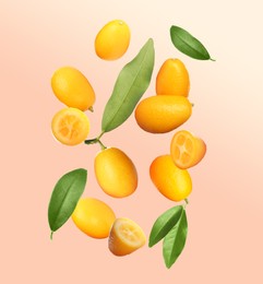 Delicious fresh kumquats and green leaves falling on pale pink background