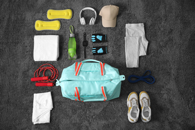 Flat lay composition with bag and sports items on grey carpet