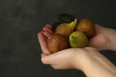 Photo of Woman holding tasty raw figs with leaf on grey background, closeup