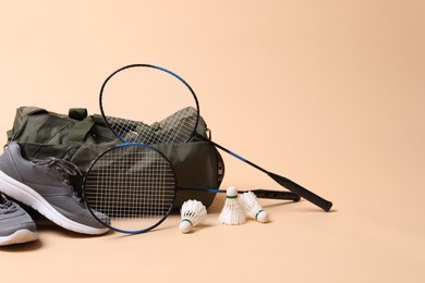Photo of Badminton set, bag and sneakers on beige background, space for text
