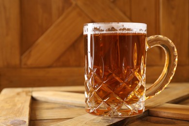 Photo of Mug with fresh beer on wooden crate, closeup. Space for text