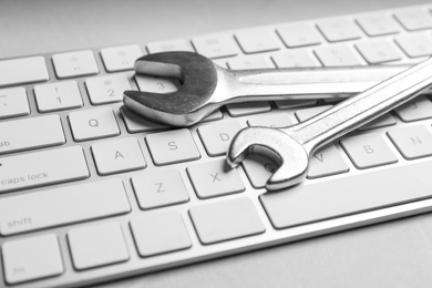 Photo of Keyboard and spanners on grey table, closeup. Concept of technical support