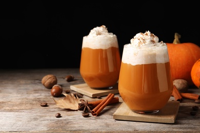 Photo of Glasses with tasty pumpkin spice latte on wooden table. Space for text