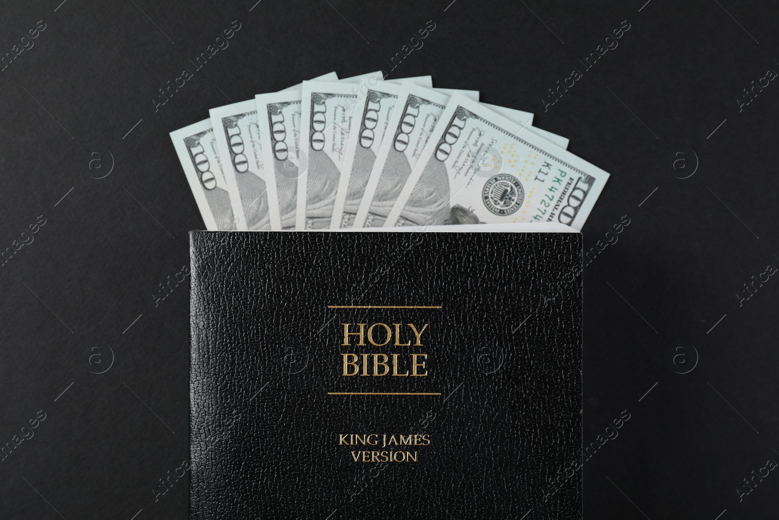 Photo of Holy Bible with money on black background, top view