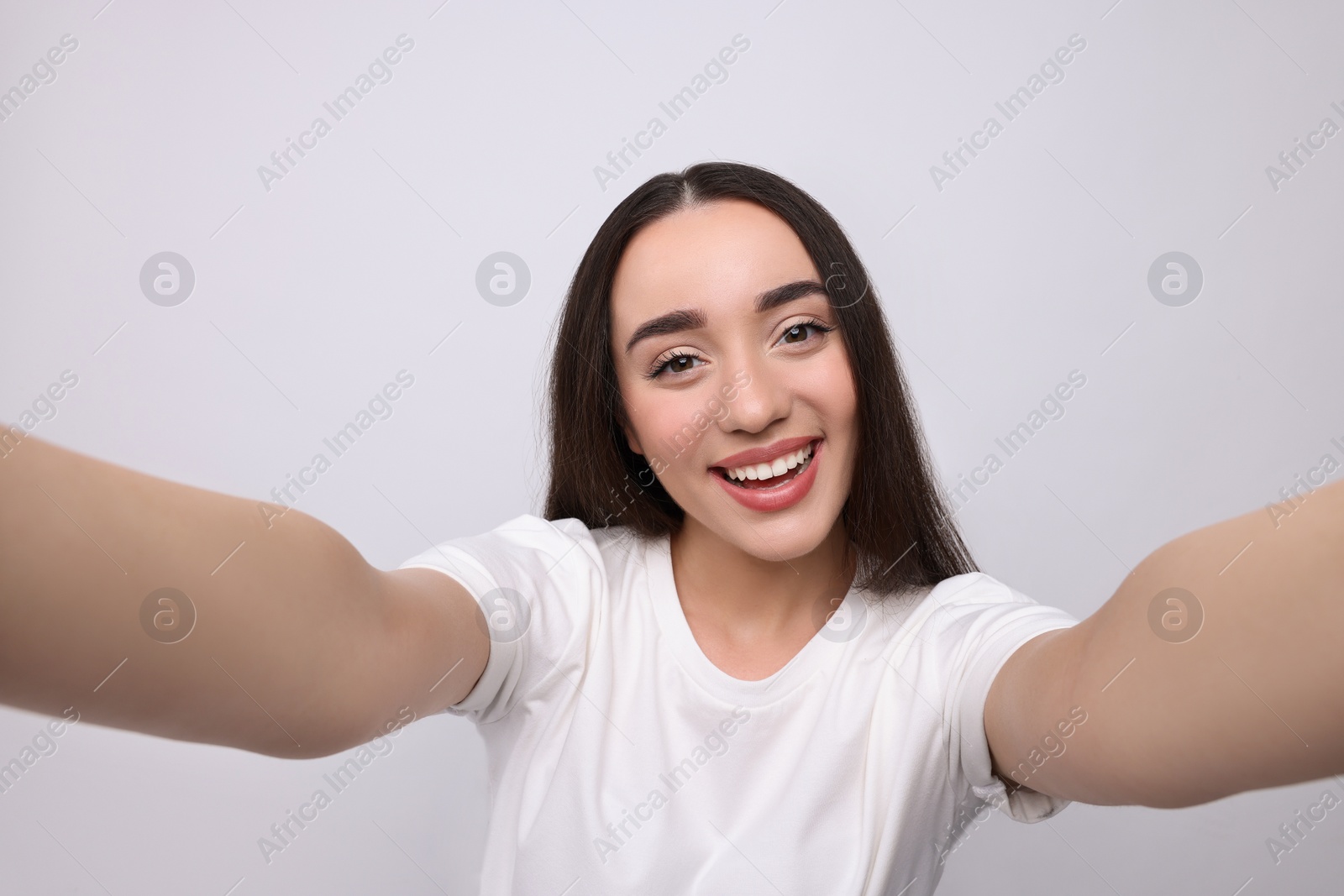 Photo of Smiling young woman taking selfie on white background