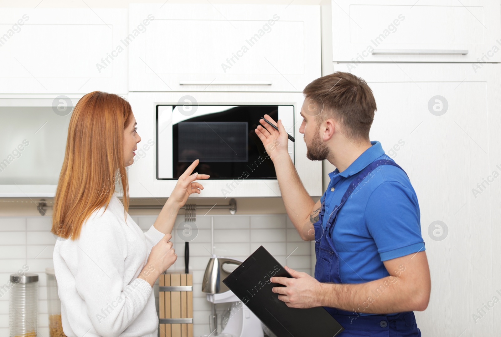 Photo of Housewife and repairman near microwave oven in kitchen