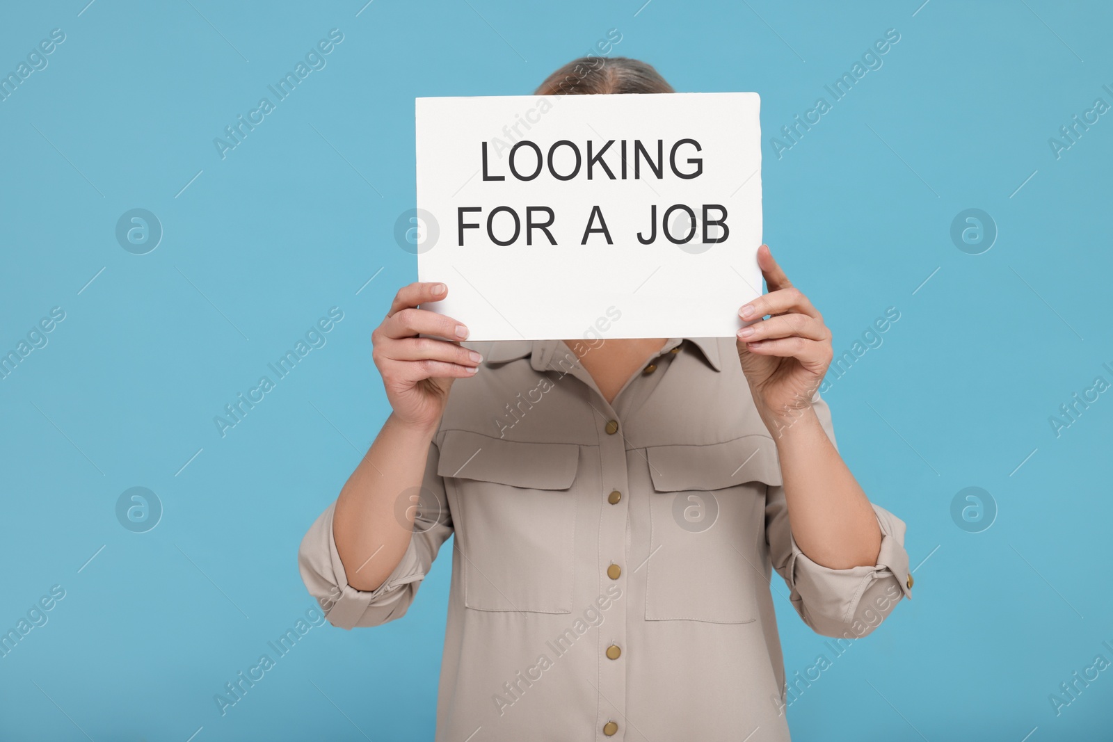 Photo of Unemployed senior woman holding cardboard sign with phrase Looking For A Job on turquoise background