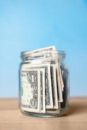 Photo of Donation jar with money on table against color background