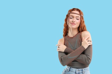Photo of Beautiful young hippie woman on light blue background, space for text