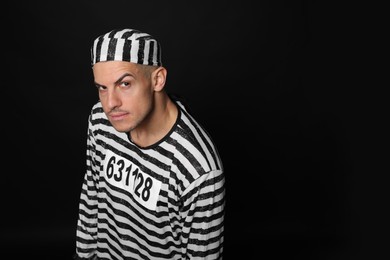 Prisoner in striped uniform on black background, space for text