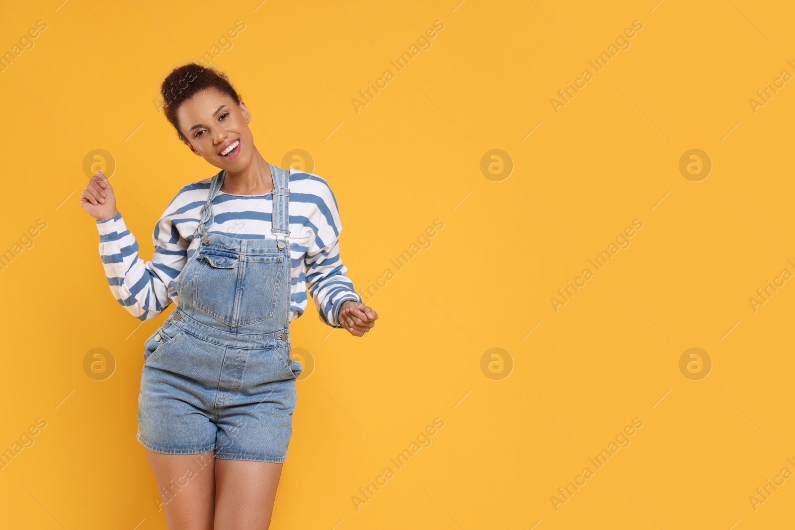 Photo of Happy young woman dancing on orange background. Space for text