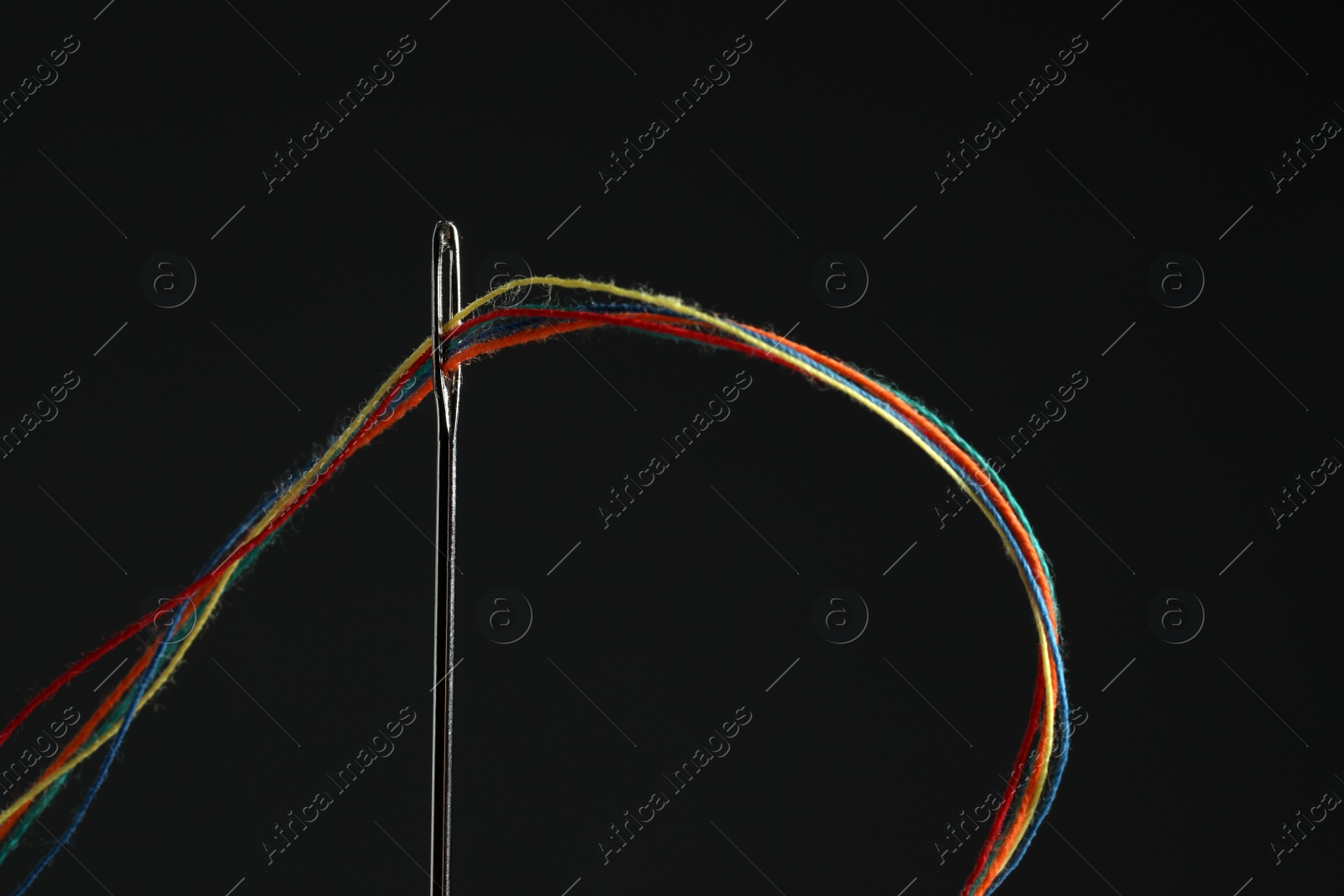 Photo of Sewing needle with colorful threads on black background