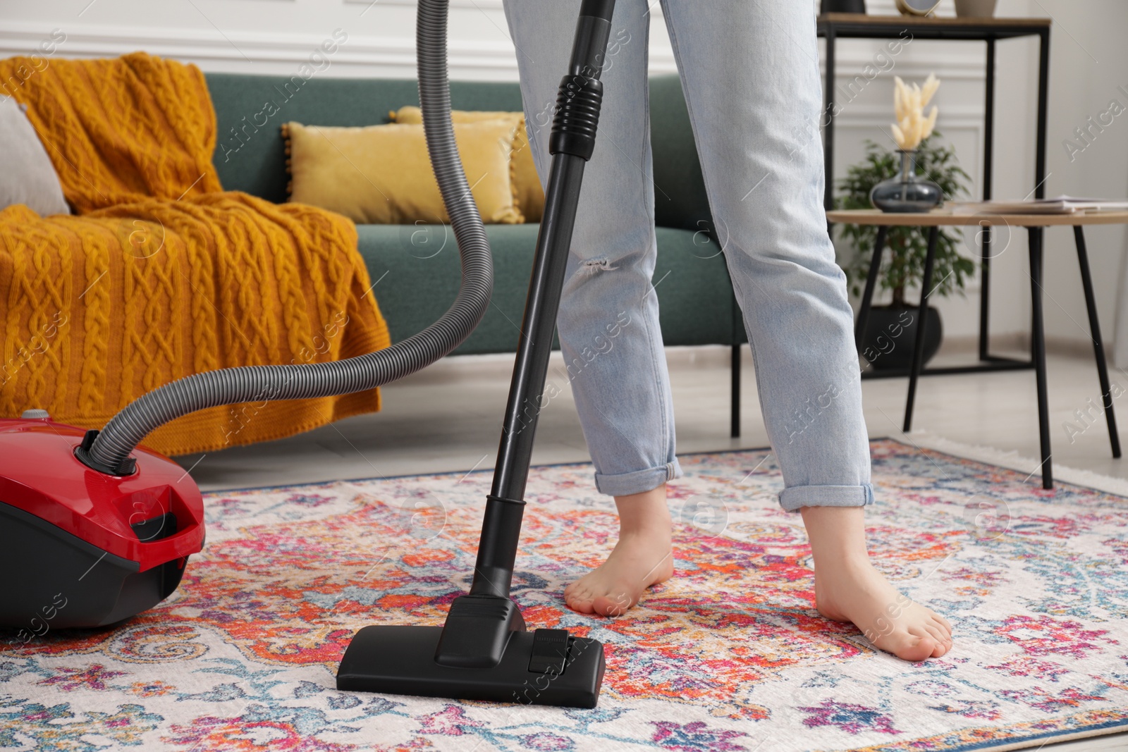 Photo of Woman cleaning carpet with vacuum cleaner at home, closeup