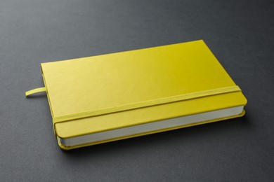 Photo of Closed notebook with blank yellow cover on black background