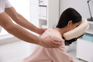 Woman receiving massage in modern chair indoors