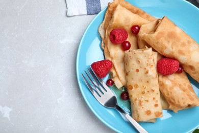 Photo of Delicious crepes served with berries on light grey table, top view. Space for text