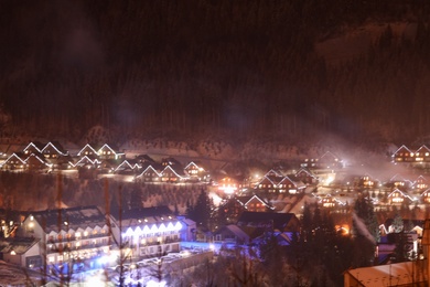 Photo of Night landscape with mountain village near forest in winter