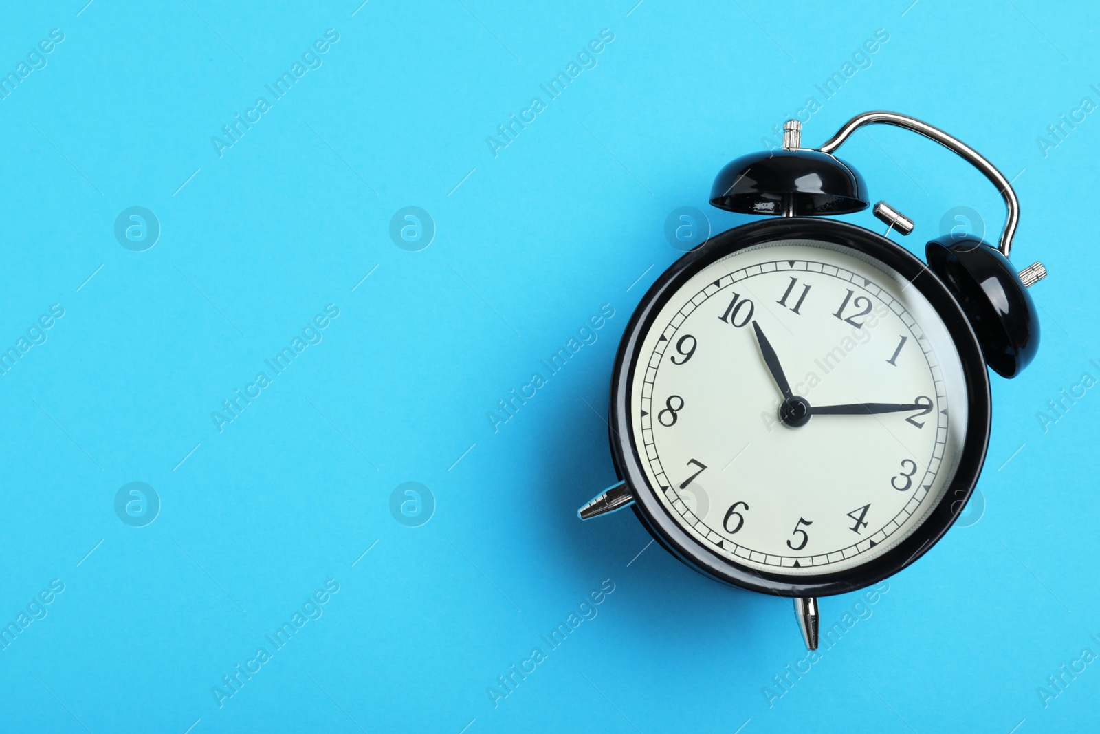 Photo of Alarm clock on light blue background, top view with space for text. School time